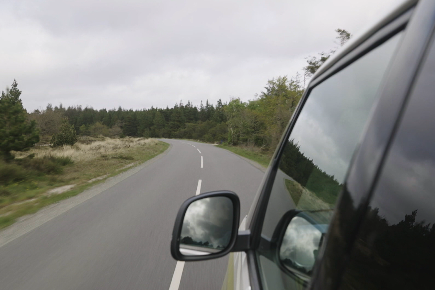 Auto rijdt op de weg in Denemarken zijspiegel