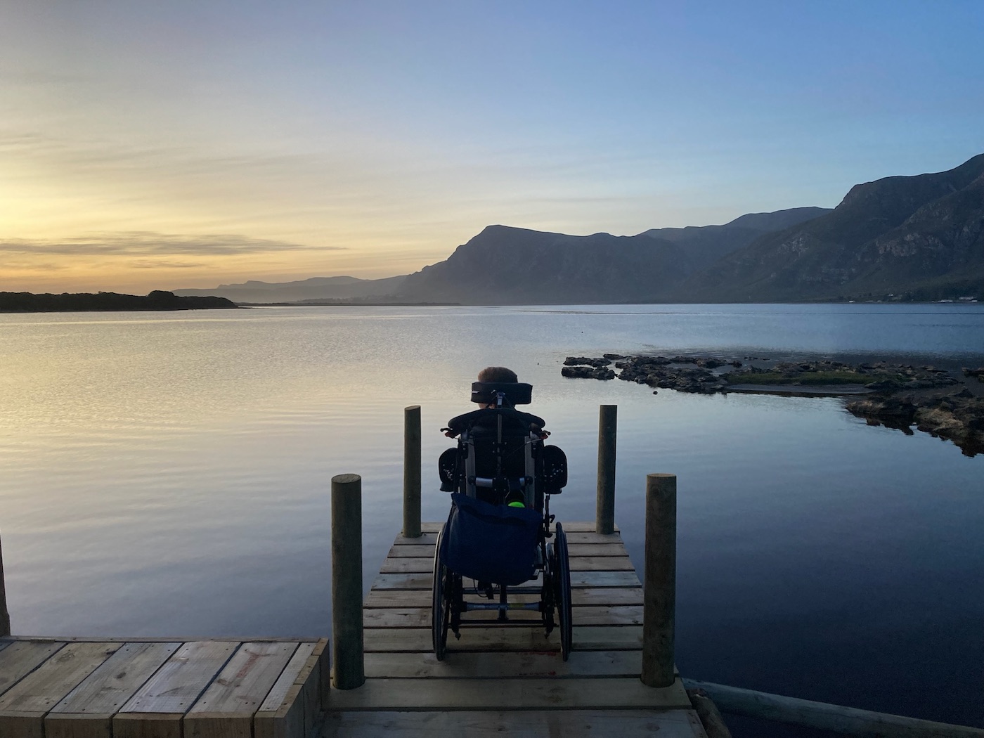Twan zit in een rolstoel aan een meer in Zuid-Afrika