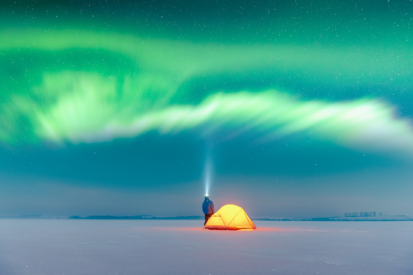 Man met lichthelm en tent op de poolcirkel kijkt naar het noorderlicht scandinavië
