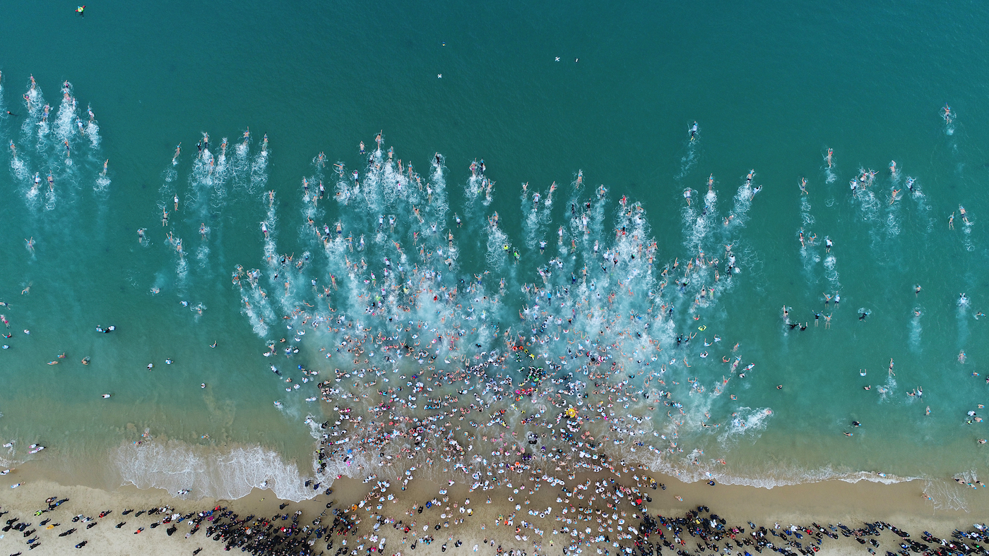 Bovenaanzicht van mensen die de zee in rennen tijdens een nieuwjaarsduik